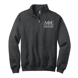 May include: A dark gray 1/4 zip sweatshirt with a white embroidered Lambda Phi Epsilon logo on the chest. The logo includes the letters "ΛΦΕ" and the words "Lambda Phi Epsilon".