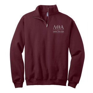May include: A maroon 1/4 zip sweatshirt with a white embroidered logo that says "ΛΘΑ Lambda Theta Alpha".