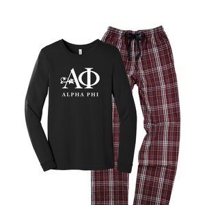 May include: Black long-sleeve shirt and plaid pajama pants. The shirt features the Greek letters Alpha Phi in white, with the text "ALPHA PHI" below. The pajama pants are red and white plaid with a drawstring waist.