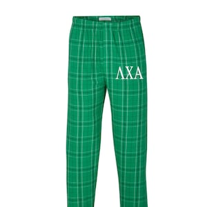 May include: Green and white plaid pajama pants with the letters "AXA" embroidered in white on the left leg.