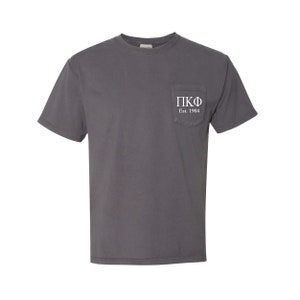 May include: A charcoal gray t-shirt with a pocket on the left side. The pocket has white text that reads "ΠΚΦ Est. 1904".