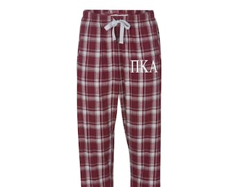 Könnte beinhalten: Rote und weiße karierte Schlafhose mit einem weißen "ΠΚΑ" Monogramm.