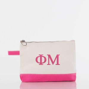 May include: A white canvas zippered pouch with a pink bottom and a pink embroidered "ΦΜ" on the front.