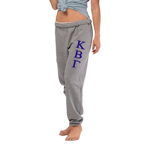 May include: Gray sweatpants with a vertical purple Greek letter design that reads "KBG".