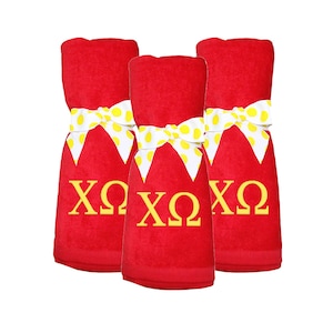 May include: Three red towels with yellow polka dot ribbon bows. Each towel has the Greek letters "XOQ" embroidered in yellow.