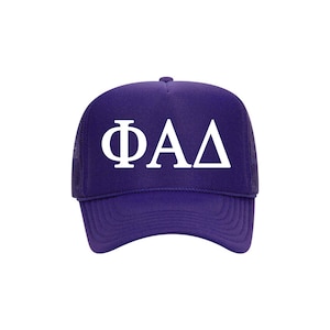 May include: Purple trucker hat with white embroidered letters that spell "ΦΑΔ".