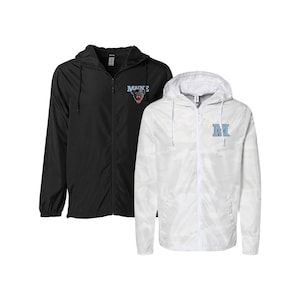 May include: Two hooded windbreakers. One is black with a white "MAINE" logo and a bear mascot. The other is white with a camouflage pattern and a blue "M" logo.