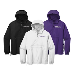 May include: Three pull-over jackets in black, white, and purple. The black jacket has "Kansas State University" embroidered on the front. The white jacket has "K-STATE" embroidered on the front. The purple jacket has "Wildcats" embroidered on the front.