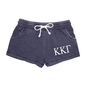 May include: Dark blue shorts with a drawstring waist and side pockets. The shorts feature the white Greek letters KKI on the front. The shorts are made of a soft, comfortable material.