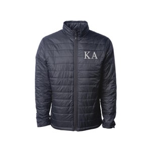 May include: A black quilted jacket with a zipper closure and a white embroidered "KA" on the left chest.