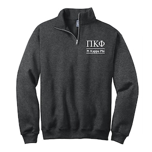 May include: A dark gray 1/4 zip sweatshirt with the Greek letters "ΠΚΦ" and the text "Pi Kappa Phi" in white.