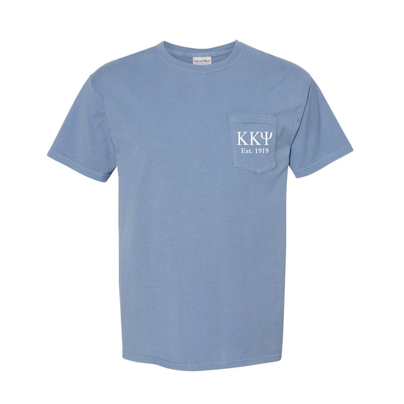 May include: A light blue t-shirt with a pocket on the left side. The pocket has white text that reads "KK&Psi; Est. 1919".