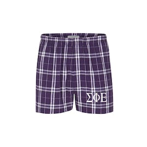 May include: Purple plaid boxer shorts with white lettering that says "ΣΦΕ".