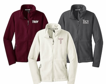 May include: Three fleece jackets in different colors: burgundy, white, and gray. The burgundy jacket has the word "TROY" embroidered on the chest in white. The white jacket has a red "T" embroidered on the chest. The gray jacket has the words "TROY UNIVERSITY" embroidered on the chest in red.