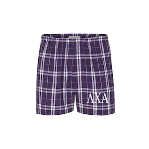 May include: Purple and white checked pyjama shorts with the Greek letters "AXA" embroidered in white on the right leg.