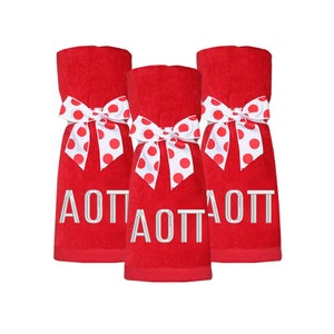 May include: Three red towels with white polka dot bows and the letters "AOT" embroidered in silver.