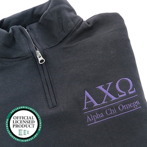 May include: A black 1/4 zip sweatshirt with a purple embroidered logo that says "AXO Alpha Chi Omega" and a green circle with the text "Official Licensed Product" in white.