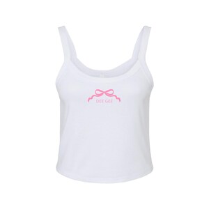 May include: White tank top with a pink bow and the text "DEE GEE" on the front.
