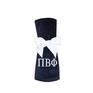 May include: A navy blue towel with a white bow and the letters "ΠΒΦ" embroidered in white.