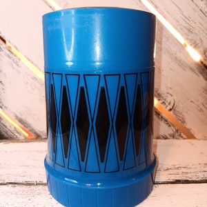 May include: A blue and black thermos with a geometric pattern. The thermos has a lid and a base.