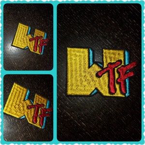 May include: A yellow embroidered patch with the letters "WTF" in red and blue. The patch is on a dark brown surface.