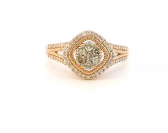 May include: A rose gold ring featuring a central cluster of seven round diamonds arranged in a square shape, surrounded by a double halo of smaller pavé-set diamonds and a split shank band adorned with additional small diamonds.