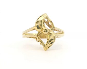 May include: A yellow gold ring featuring two leaf-shaped elements arranged in a bypass design. Each leaf has a textured, faceted surface with a polished finish. A small, smooth gold sphere is positioned between the two leaves at the center.