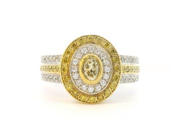 May include: A multi-layered oval ring featuring a central light yellow stone surrounded by a halo of clear white stones, encased in a yellow gold frame, with an outer border of yellow stones and a band of white and yellow stones.
