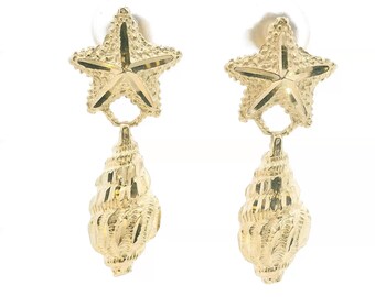 May include: A pair of gold drop earrings featuring a textured starfish stud connected to a dangling seashell charm. The metal has a polished, reflective finish with intricate detailing on both the starfish and the spiral shell components.