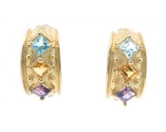 May include: A pair of gold hoop earrings featuring a vertical row of three square-cut gemstones in light blue, yellow, and purple, accented by small gold spheres on a textured gold band with a polished finish.