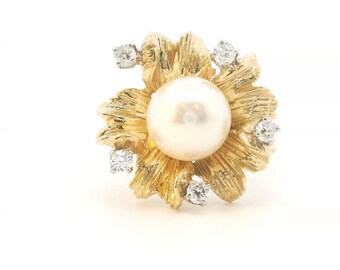 May include: A yellow gold ring featuring a central round white pearl surrounded by textured, petal-like gold leaves. Five small, clear round-cut diamonds are set at intervals among the gold petals, creating a floral-inspired design.