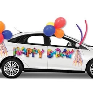 May include: A white car decorated with colourful balloons and streamers for a birthday celebration. The car has the words "HAPPY B'DAY" displayed on the side.