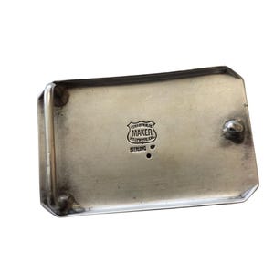 Puede incluir: Hebilla de cintur&oacute;n rectangular plateada con esquinas redondeadas. La hebilla tiene la marca del fabricante "MAKER HOLLYWOOD, CA" y "STERLING". Tiene un peque&ntilde;o bot&oacute;n redondeado en un lado.