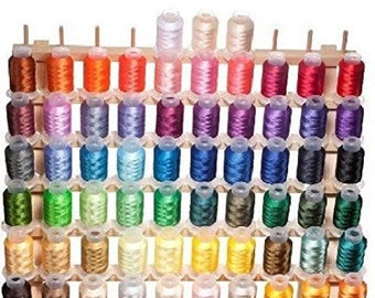 May include: A wooden thread spool organizer filled with colorful embroidery thread. The spools are arranged in neat rows, showcasing a wide spectrum of colors, including shades of red, blue, green, yellow, and purple. The thread is wound on small spools.