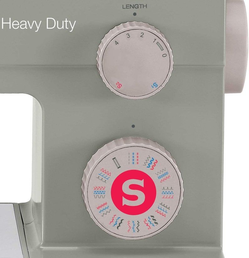May include: A gray sewing machine with a white label that reads "Heavy Duty". The machine has two dials, one for stitch length and one for stitch selection. The stitch selection dial has a red "S" in the center and shows a variety of stitch patterns.