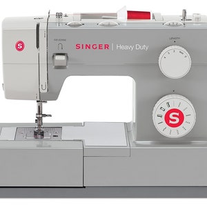 May include: A gray Singer Heavy Duty sewing machine with a white stitch selection dial and a white stitch length dial. The machine has a red thread spool and a red button for reverse stitching.