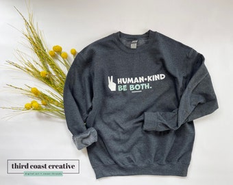May include: Dark gray sweatshirt with a white peace sign and the text "HUMAN-KIND BE BOTH."