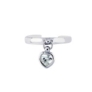 May include: A silver ear cuff with a dangling heart-shaped charm that has a clear crystal in the center.