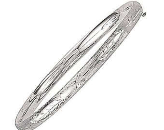 May include: A silver bangle bracelet with a hinged clasp. The bracelet has a polished, smooth surface with etched floral and leaf patterns along the edges. The bangle is oval-shaped and reflects light.