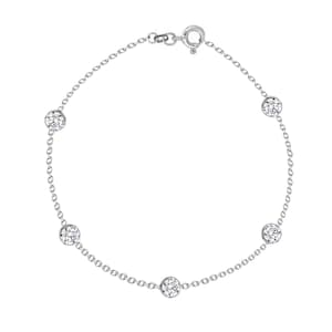 May include: A delicate silver bracelet featuring five round, clear gemstones evenly spaced along a fine chain. The bracelet has a simple clasp closure and is designed to be worn on the wrist. The gemstones sparkle against the silver chain.