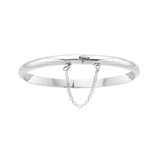 May include: A silver bangle bracelet with a hinged clasp and a delicate chain dangling from the clasp.