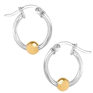 May include: A pair of silver hoop earrings with a gold-colored bead accent. The earrings have a classic design with a hinged closure. The gold bead adds a touch of elegance to the simple, circular shape.