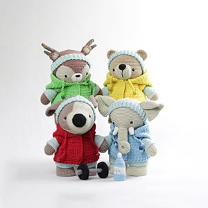 Puede incluir: Cuatro animales de peluche tejidos a crochet con chaquetas con capucha. Los animales son un ciervo, un oso, un perro y un elefante. El ciervo lleva una chaqueta verde, el oso lleva una chaqueta amarilla, el perro lleva una chaqueta roja y el elefante lleva una chaqueta azul.