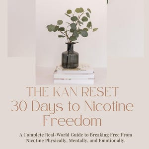 May include: A book titled "THE KAN RESET 30 Days to Nicotine Freedom" with text describing a guide to breaking free from nicotine. A small, dark glass vase holds leafy branches, resting on a stack of books. The background is a soft, neutral color.