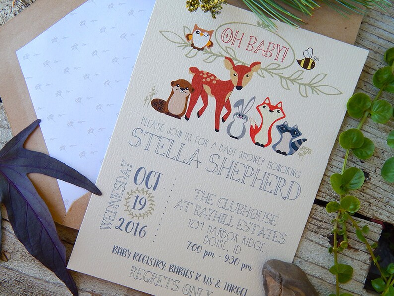 May include: Baby shower invitation featuring woodland animals, including a deer, fox, and raccoon. The invitation reads "Oh Baby!" and includes the date, time, and location for the event. The invitation is printed on cream-colored paper.
