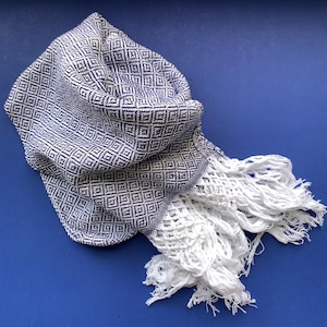 May include: A blue and white woven shawl with a diamond pattern and white fringe.