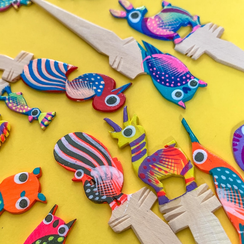 May include: A collection of colorful wooden animal figurines, including a rooster, a unicorn, a bird, and a few others. The figurines are painted in bright colors and have intricate details.