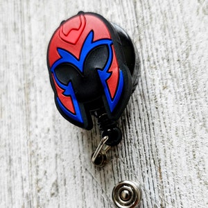 Puede incluir: Un portagafete retráctil negro y rojo con una imagen de dibujos animados del casco de Magneto de los cómics de X-Men.