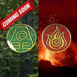 May include: Two circular pins, one green with a swirl and geometric design, the other red with a flame design. Both have gold borders and glittery textures. The words "COMING SOON" are in a red banner across the top.