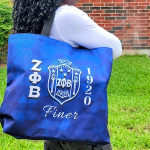 May include: A blue tote bag with white text and a crest. The bag features the letters "NFB" on the left side and the number "1920" on the right. The crest in the center includes the letters "ZFB" and the word "Finer" at the bottom.